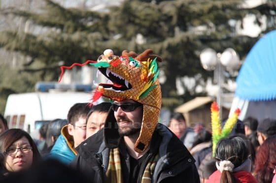 A foreigner with a dragon hat drops is lost in the sea of people