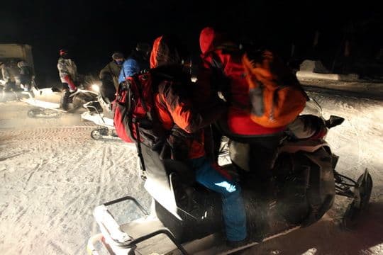 Two passengers share one snowmobile.